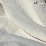 the One Preevay Faux Rabbit Fur Throw in Pure White. Inspired by the elegance of Fernando Botero and crafted from ultra-premium faux rabbit fur. Hypoallergenic, cruelty-free, over the sofa very white