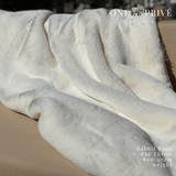 the One Preevay Faux Rabbit Fur Throw in Pure White. Inspired by the elegance of Fernando Botero and crafted from ultra-premium faux rabbit fur. Hypoallergenic, cruelty-free, over the sofa