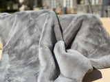 ONE Preevay's Faux Rabbit Fur Throw in Dramatic Gray. Inspired by Fernando Botero, crafted from Ultra Premium Faux Rabbit Fur. Hypoallergenic, cruelty-free, and lined with elegant velvet for refined warmth