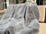 ONE Preevay's Faux Rabbit Fur Throw in Dramatic Gray. Inspired by Fernando Botero, crafted from Ultra Premium Faux Rabbit Fur. Hypoallergenic, cruelty-free, and lined with elegant velvet for refined warmth over the sofa layout.