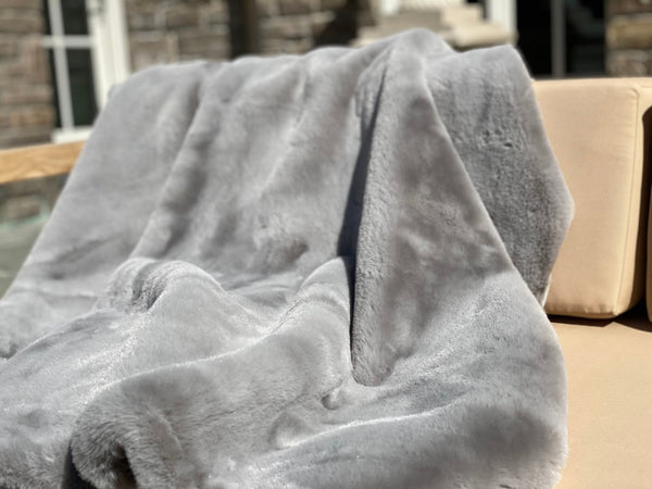 ONE Preevay's Faux Rabbit Fur Throw in Dramatic Gray. Inspired by Fernando Botero, crafted from Ultra Premium Faux Rabbit Fur. Hypoallergenic, cruelty-free, and lined with elegant velvet for refined warmth over the sofa layout.