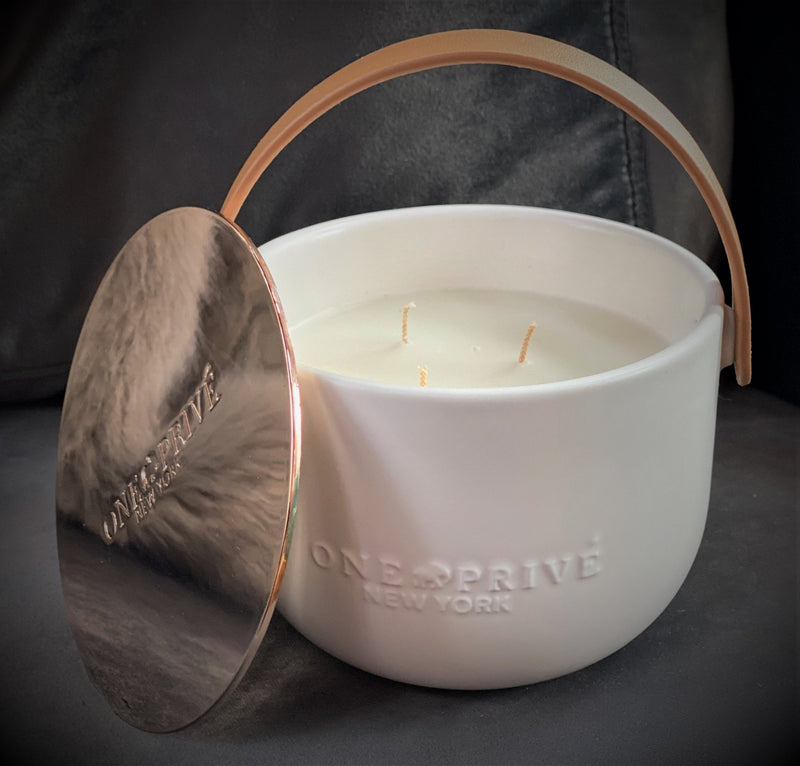 Indulge in the Bergamot and Clove Perfumed Estate Candle from One Preevay. Handcrafted with premium essential oils and soy wax, it features a stunning porcelain bowl with a silver-plated lid and leather strap. Elevate your ambiance with leather and porcelain
